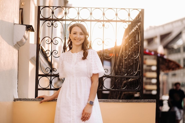 Una mujer hermosa con un vestido blanco al atardecer en la ciudad Fotografía callejera nocturna