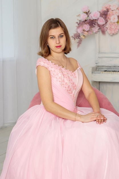 Una mujer hermosa con un vestido largo rosa en un salón con flores La chica es bonita SESIÓN FOTOGRÁFICA DE PRIMAVERA