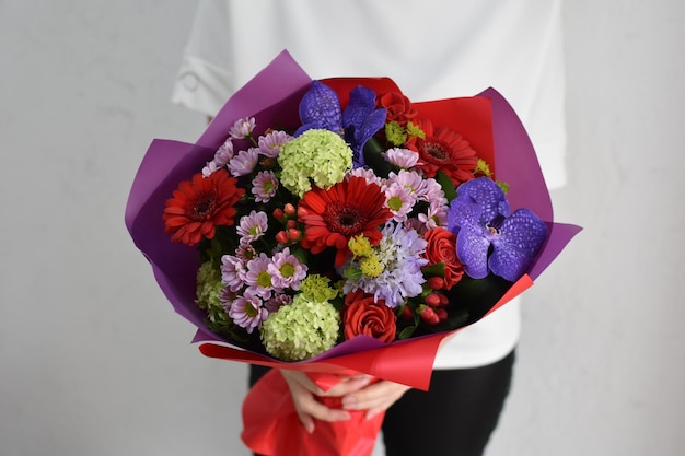 Mujer con hermosas flores en las manos en el interior de fondo ramo de flores para floristería