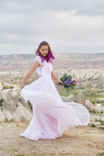 Mujer con un hermoso ramo de flores en sus manos bailar en la montaña