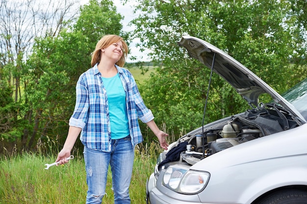 Mujer con herramientas cerca de auto roto