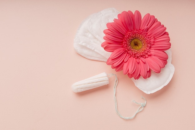 Mujer higiene protección menstruación toallas sanitarias y tampones con flor sobre un fondo rosa