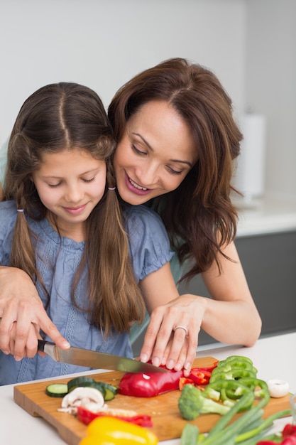 Mujer, con, hija, cortar, vegetales, en, cocina