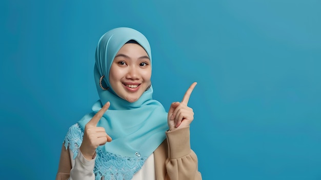 Mujer hijab apuntando al espacio de copia aislado en fondo azul