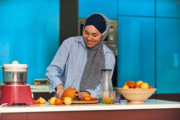 Mujer hijab árabe haciendo jugo de fruta en la cocina moderna Concepto de hogar Concepto de estilo de vida saludable Enfoque selectivo Foto de alta calidad