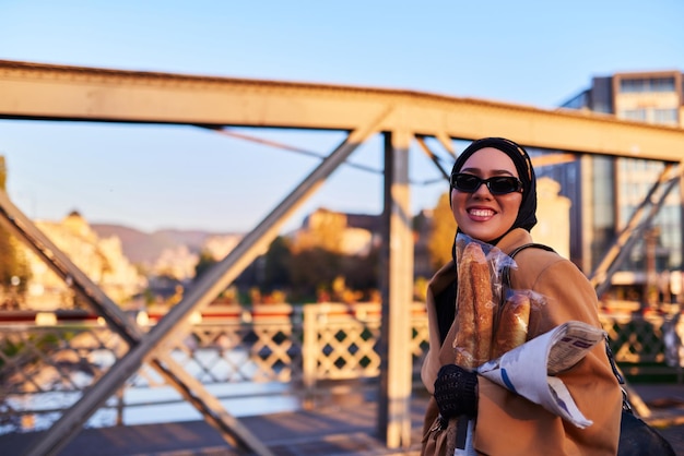 Una mujer hijab con elegantes gafas de sol y un elegante traje francés caminando por la ciudad al atardecer