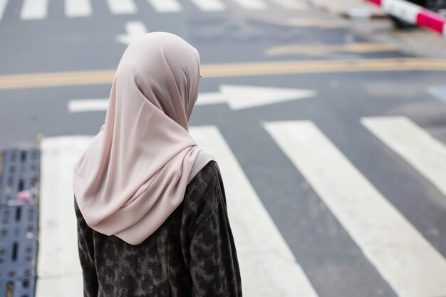 Mujer con hijab esperando en un cruce de peatones