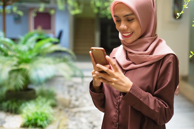 una mujer con hijab mira su teléfono.