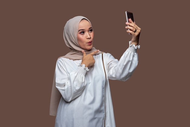 Mujer con hijab se toma una selfie con un teléfono inteligente