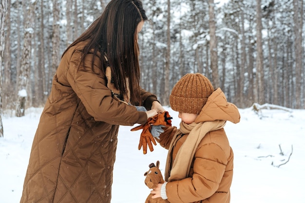 Mujer con un hijo pequeño en una caminata de invierno en el bosque nevado