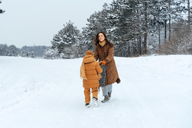 Mujer con un hijo pequeño en una caminata de invierno en el bosque nevado