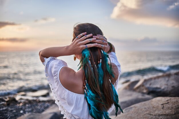 Mujer hippie con plumas azules en el cabello