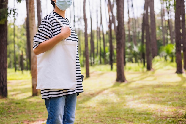 Mujer hipster con bolsa de algodón blanco en el parque