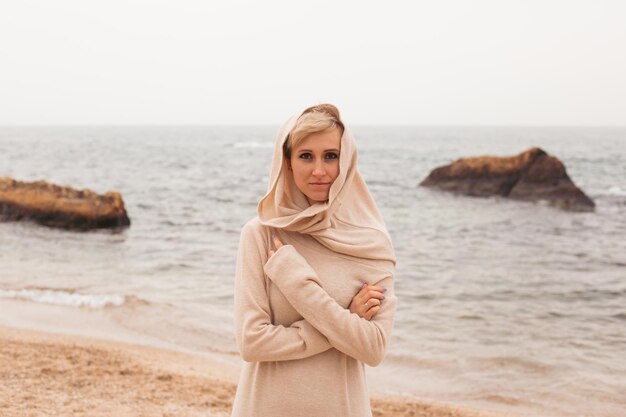 Mujer hipster caminando en la playa de arena cerca del primer plano del mar