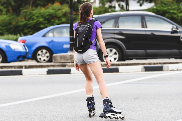 Mujer hipster con patín en la carretera de la ciudad