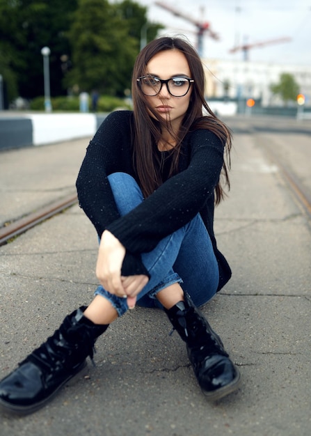 Mujer hipster sentada en la carretera en verano en la ciudad El concepto de estilo de vida y moda