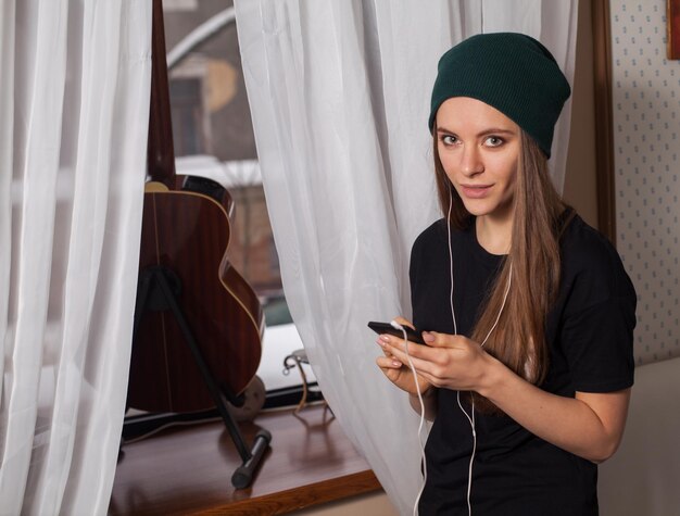 Mujer hipster con sombrero verde escuchando música y disfrutando de la vida