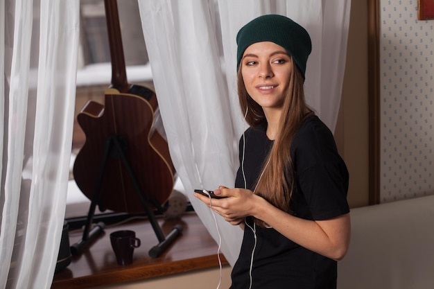 Mujer hipster con sombrero verde escuchando música y disfrutando de la vida