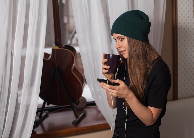 Mujer hipster con sombrero verde escuchando música y disfrutando de la vida