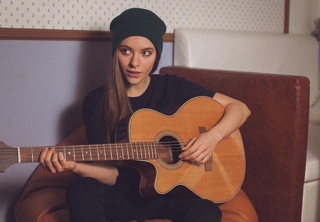 Mujer hipster tocando la guitarra y disfrutando de la música