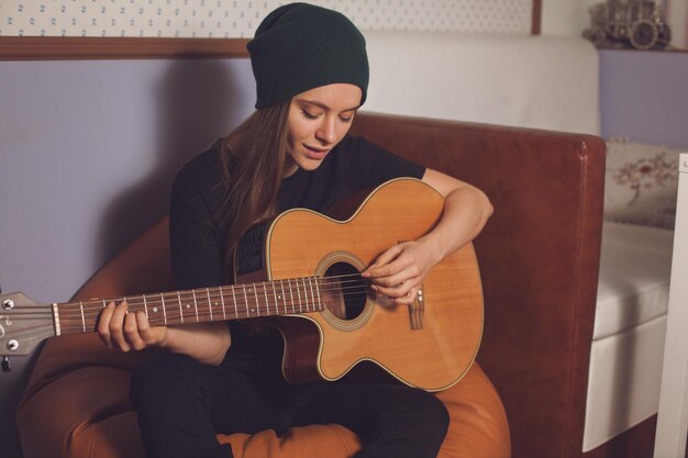 Mujer hipster tocando la guitarra y disfrutando de la música