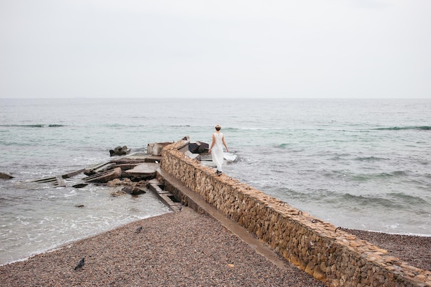 Mujer hipster con vestido cerca del mar en otoño