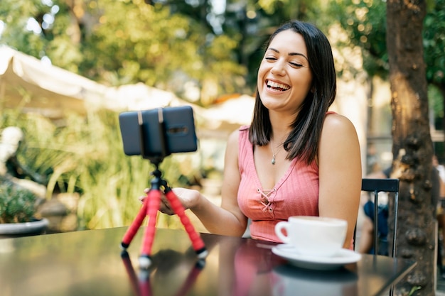 Foto mujer hispana alegre grabando video para su vlog en teléfono móvil