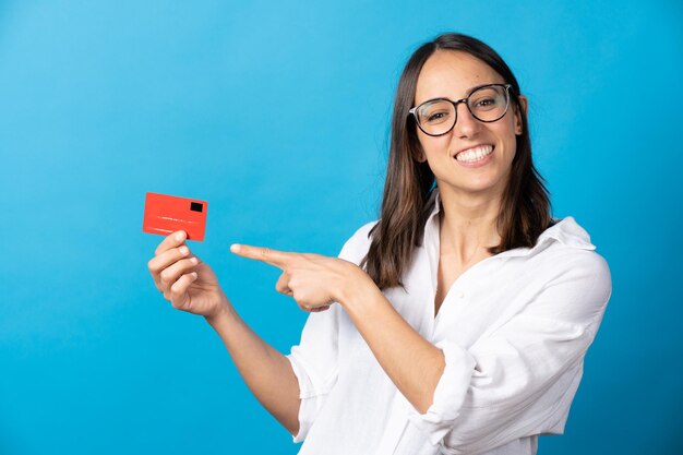 Mujer hispana alegre que señala en la tarjeta de crédito