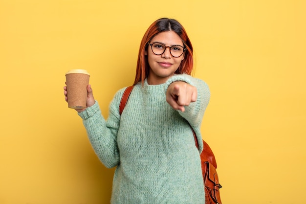 Mujer hispana apuntando a la cámara eligiéndote. estudiante con un concepto de café