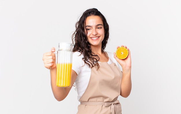 Mujer hispana bonita chef preparando un jugo de naranja