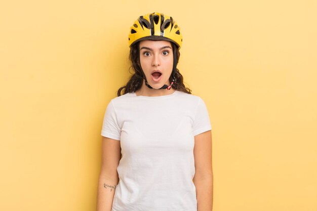 Mujer hispana bonita joven que parece muy conmocionada o sorprendida concepto de bicicleta