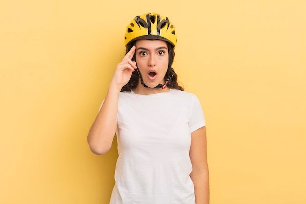 Mujer hispana bonita joven que parece sorprendida, dándose cuenta de un nuevo pensamiento, idea o concepto. concepto de bicicleta