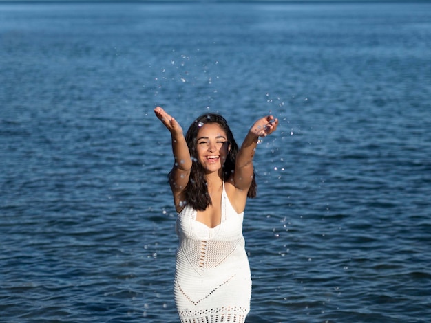 Mujer hispana despreocupada salpicando agua a la cámara en el mar