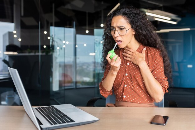 Mujer hispana enferma en oficina mujer de negocios tiene dolor de garganta dolor de garganta usa medicamentos para el dolor