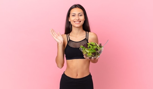 Mujer hispana de fitness que se siente feliz, sorprendida al darse cuenta de una solución o idea y sosteniendo una ensalada