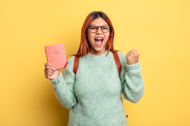 Mujer hispana gritando agresivamente con una expresión enojada estudiante y concepto de calendario