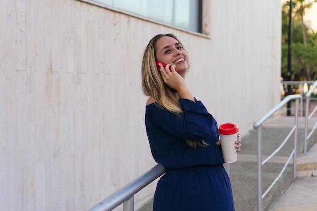 Mujer hispana hablando por teléfono inteligente mientras está de pie en la calle