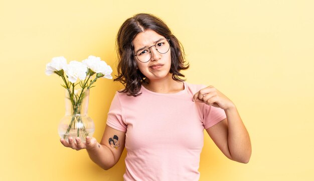 Mujer hispana joven que parece arrogante, exitosa, positiva y orgullosa. concepto de maceta de flores