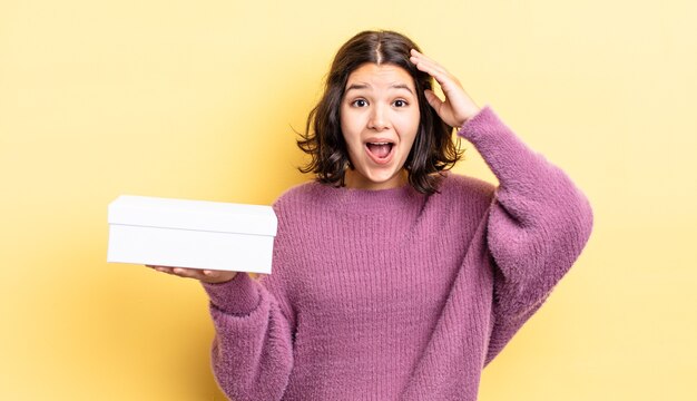 Mujer hispana joven que parece feliz, asombrada y sorprendida. concepto de caja en blanco