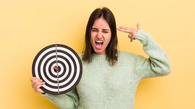 Foto mujer hispana joven que parece infeliz y estresada gesto de suicidio haciendo concepto de objetivo de dardos de signo de pistola