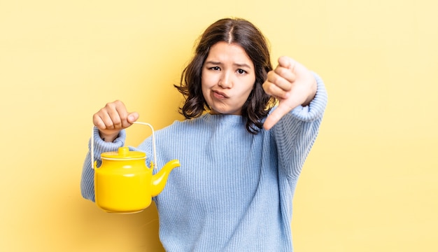 Mujer hispana joven que se siente cruzada, mostrando los pulgares hacia abajo. concepto de tetera