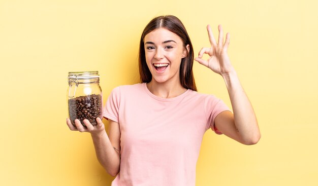 Mujer hispana joven que se siente feliz, mostrando aprobación con gesto bien. concepto de granos de cafe