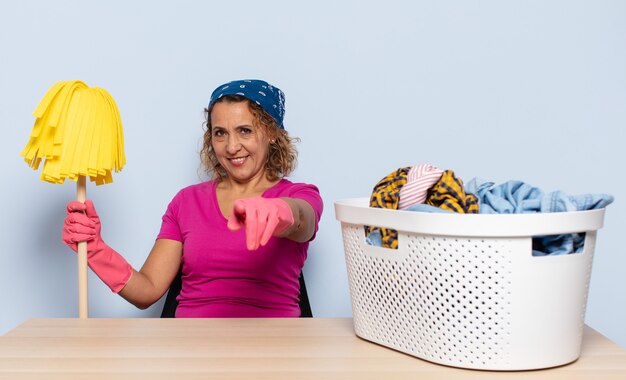 Mujer hispana de mediana edad apuntando al frente con una sonrisa satisfecha, confiada y amistosa, eligiéndote