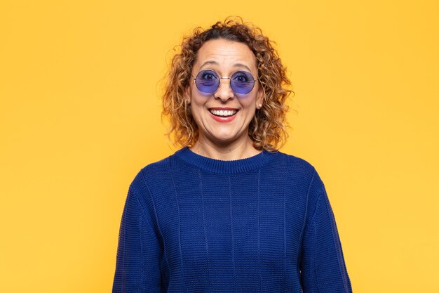 Mujer hispana de mediana edad que parece feliz y gratamente sorprendida, emocionada con una expresión fascinada y conmocionada