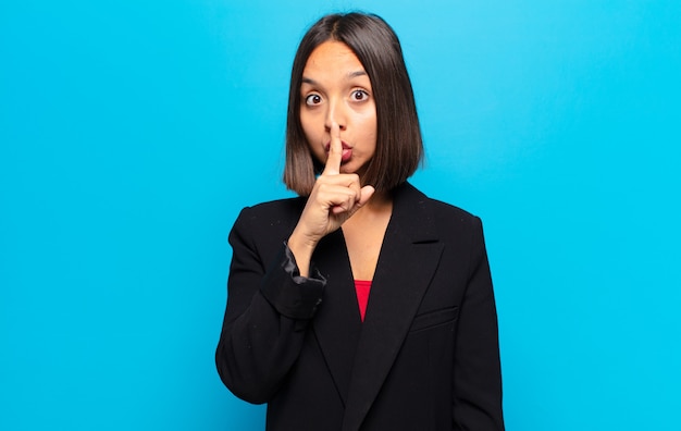 Mujer hispana pidiendo silencio y silencio, gesticulando con el dedo delante de la boca, diciendo shh o guardando un secreto