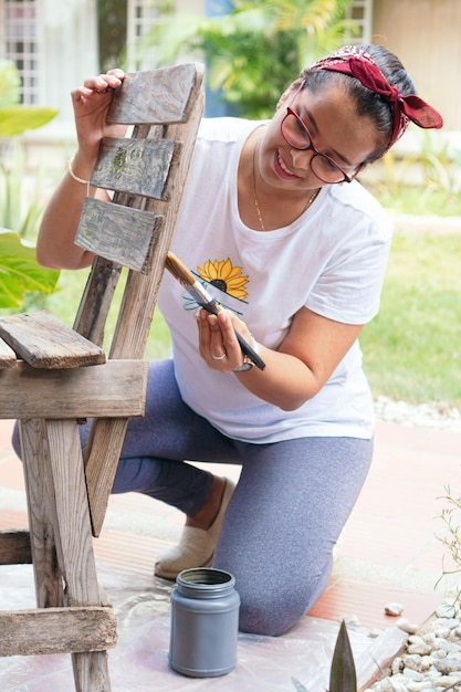 Foto la mujer hispana está pintando una silla en casa