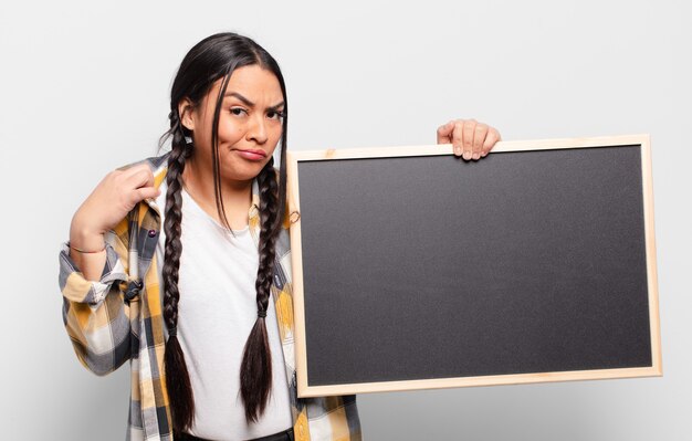 Mujer hispana que parece arrogante, exitosa, positiva y orgullosa, apuntando a sí misma