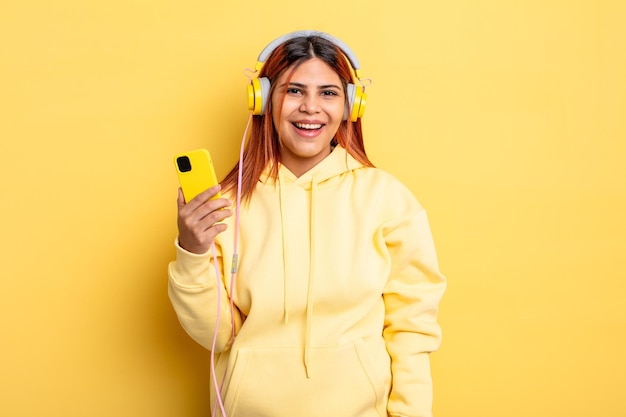 Mujer hispana que parece feliz y gratamente sorprendida. auriculares y concepto de teléfono inteligente