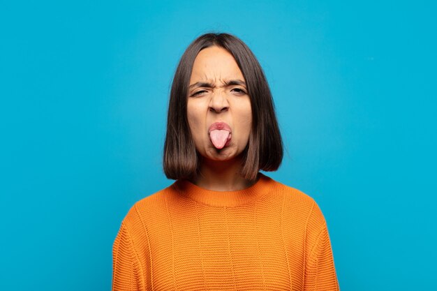 Mujer hispana que se siente disgustada e irritada, que saca la lengua, que no le gusta algo desagradable y asqueroso