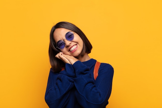 Mujer hispana que se siente enamorada y se ve linda, adorable y feliz, sonriendo románticamente con las manos al lado de la cara